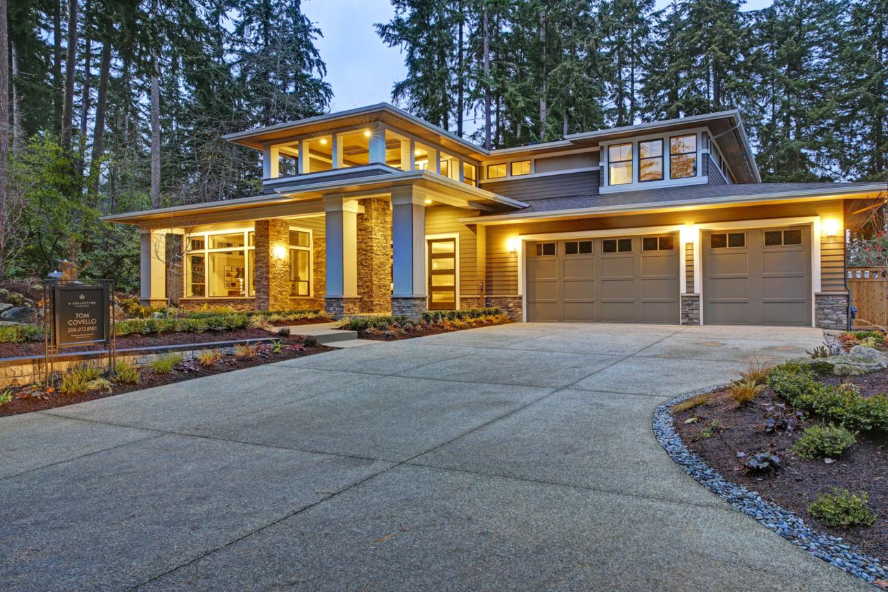Modern two-story house with large windows, double garage, and illuminated exterior at dusk—contact for details.